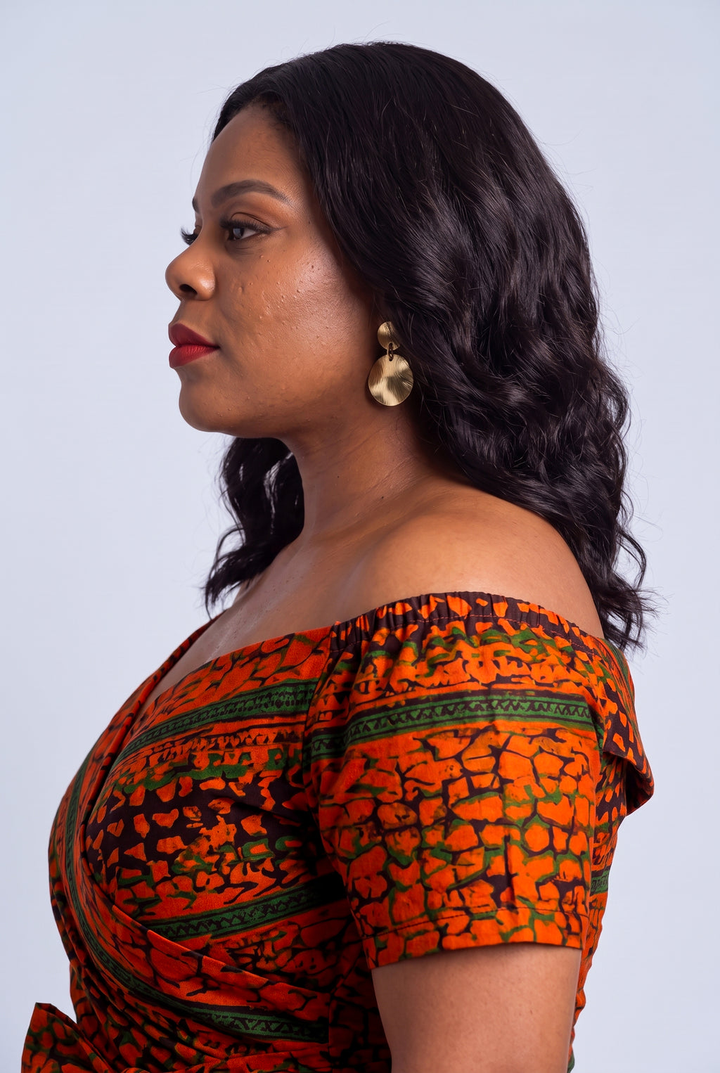 Detailed shot of the elasticated off shoulder neckline framing the collarbone on a premium Ankara wedding guest dress