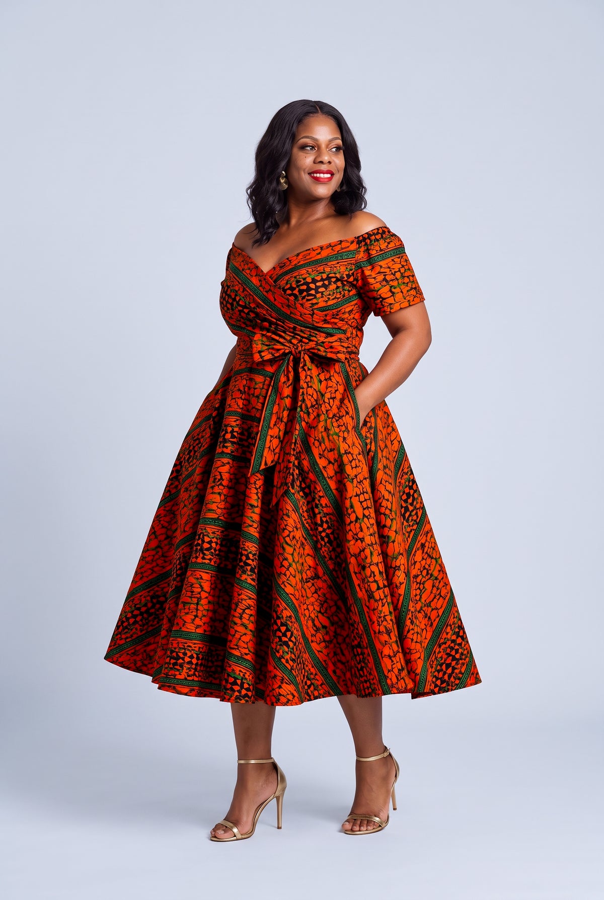 Plus size model wearing Amber Horizon orange and green Ankara off shoulder dress