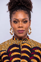 A close-up portrait of a woman  wearing a vibrant yellow, black, and red patterned Ankara shirt  dress 