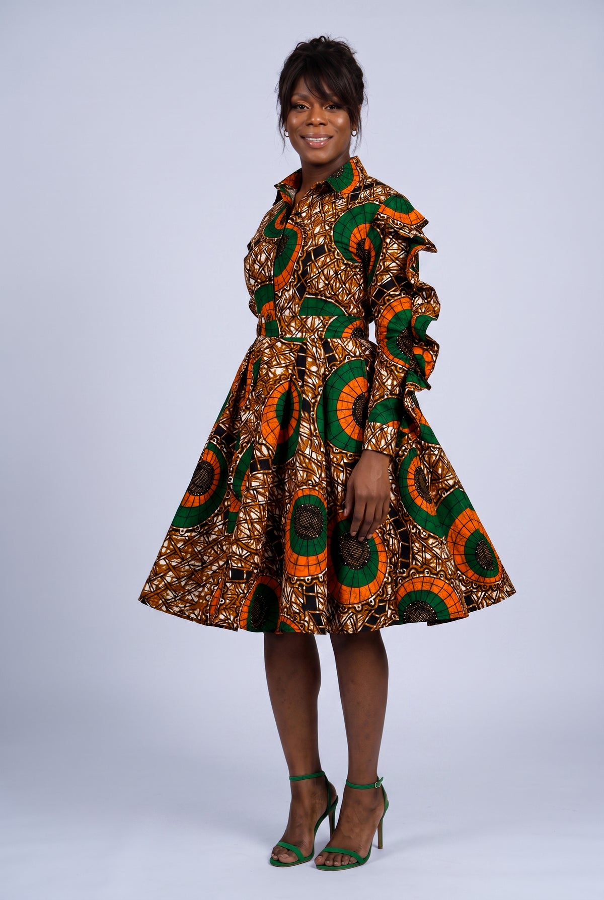 Side turned view of an orange African print shirt dress showing flare skirt movement 