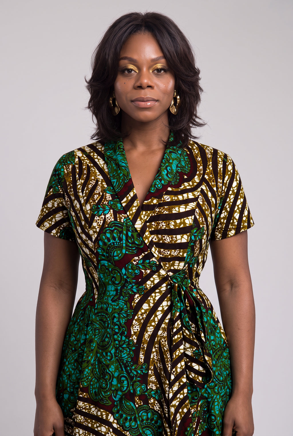 Half-length front view of green and gold African wax print dress. 