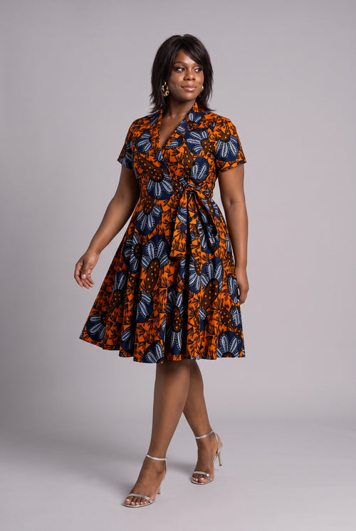 Model walking in orange African print wrap midi dress with pockets