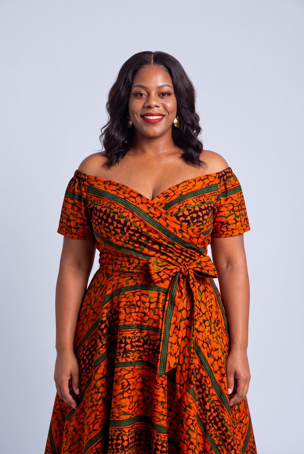 Fitted bodice and full circle flare skirt silhouette on a curve model wearing a  orange Ankara off-shoulder dress