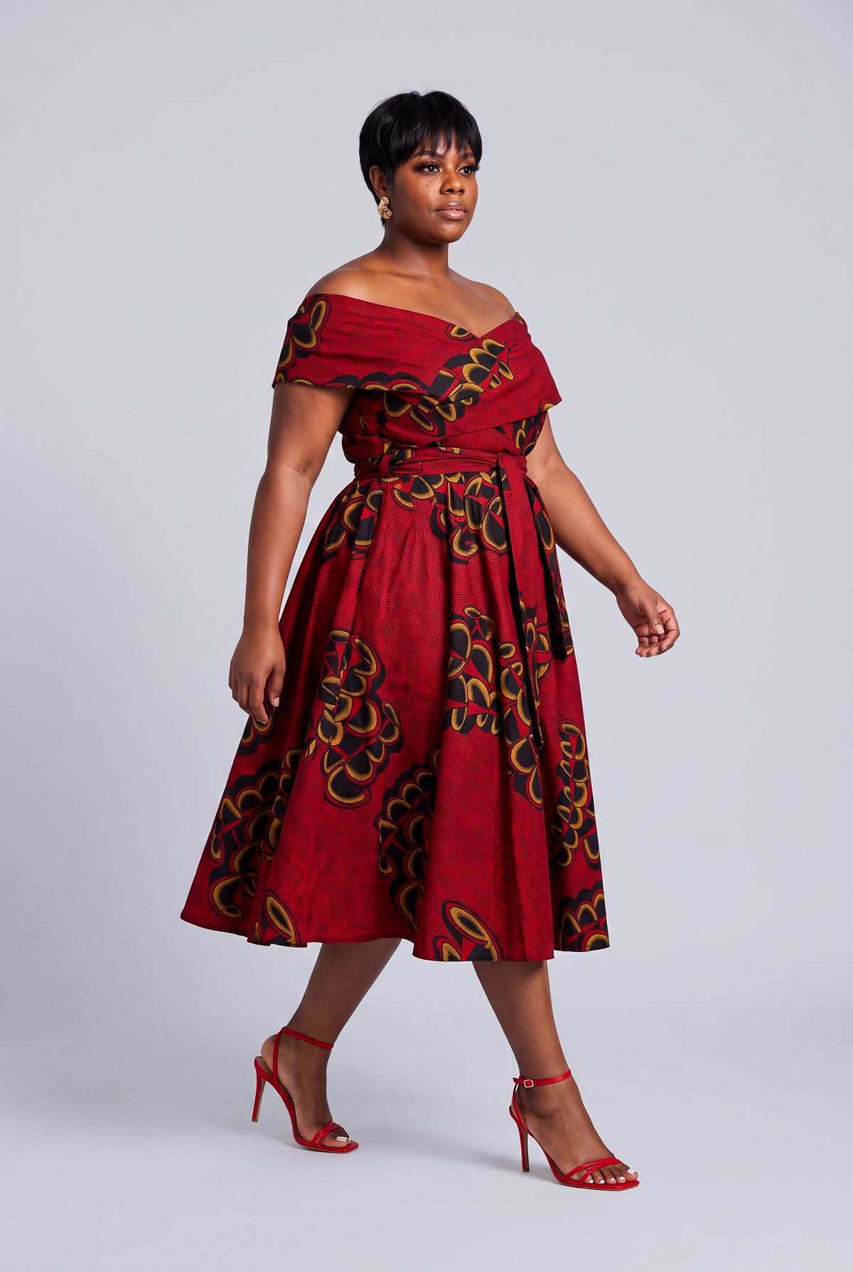 A curvy model showcasing a plus size red African dress 