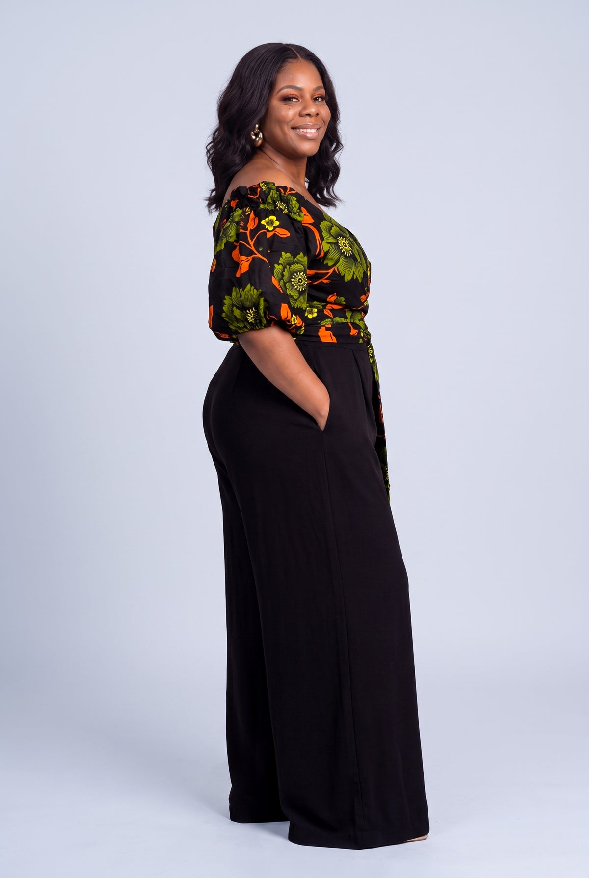 Side view of Olive Oasis orange and green Ankara wrap top styled with black palazzo trousers