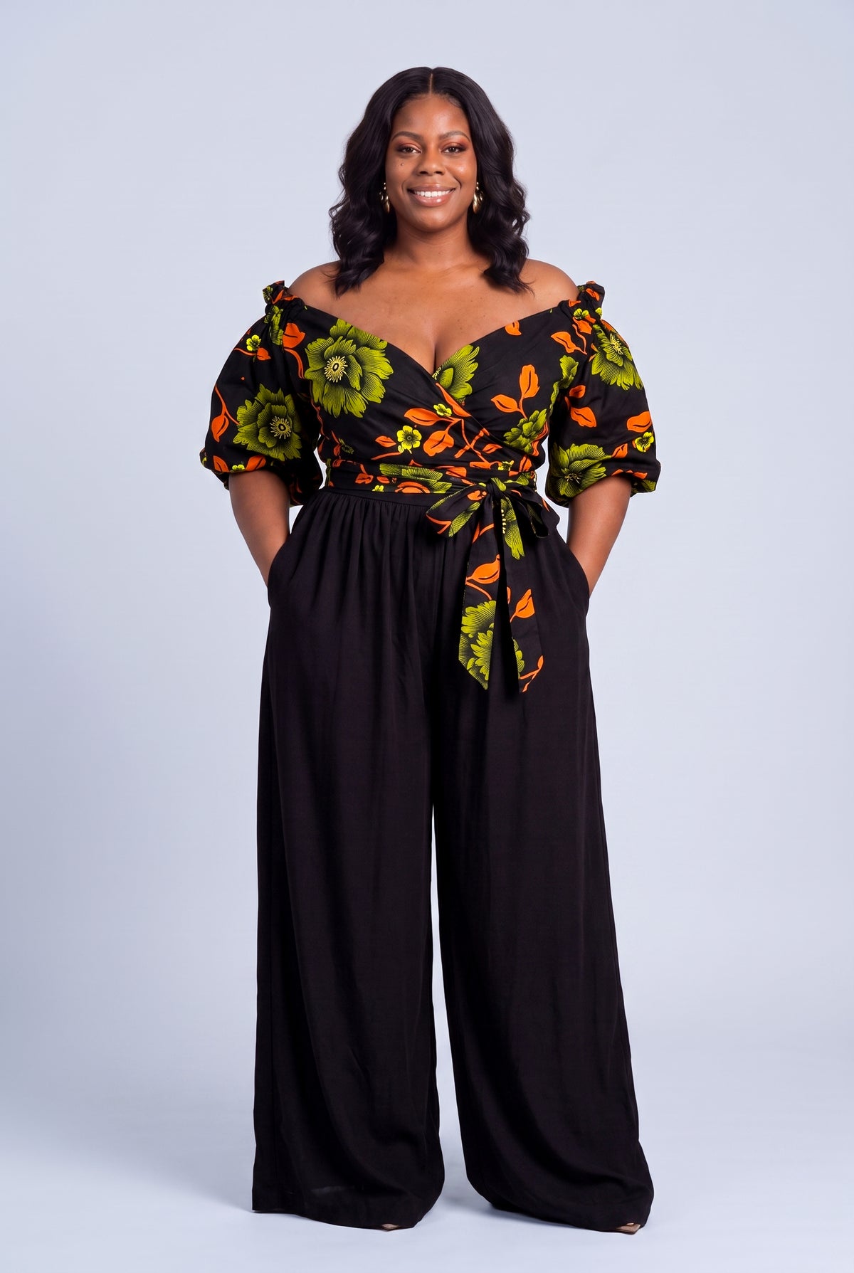 Plus size model wearing Olive Oasis orange and green Ankara wrap top with black palazzo trousers