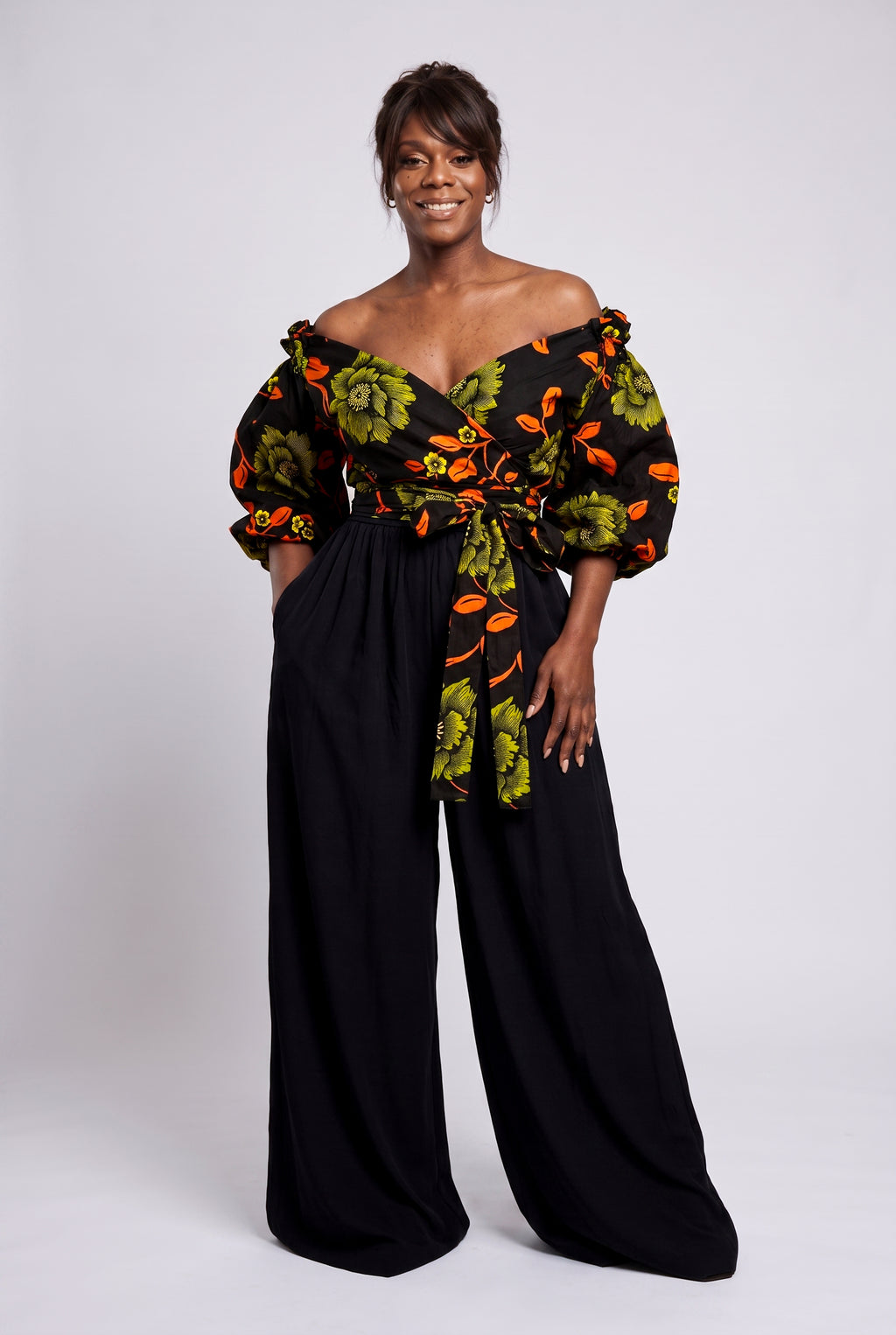 Full length view of Olive Oasis African print wrap top paired with flowing black palazzo trousers