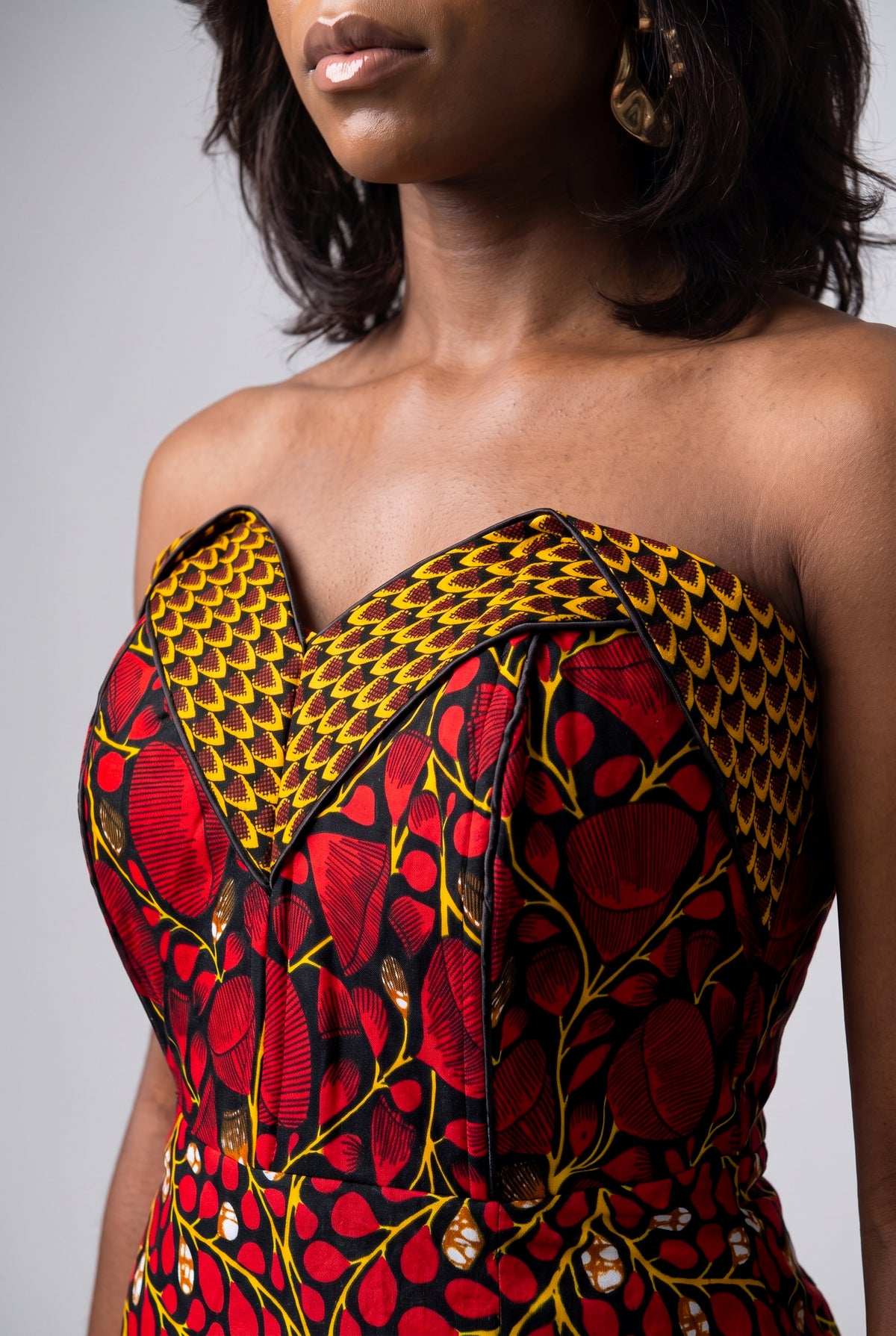 A close-up of a model wearing a strapless African wax print dress with a sweetheart neckline.