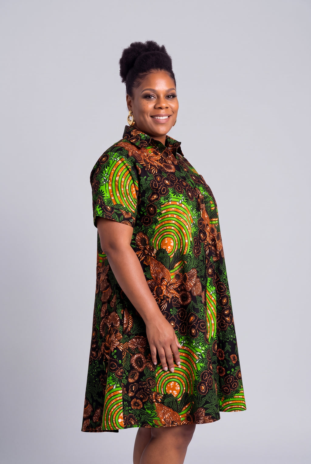 Side view profile of a curvy model wearing the green geometric Ankara shirt dress 