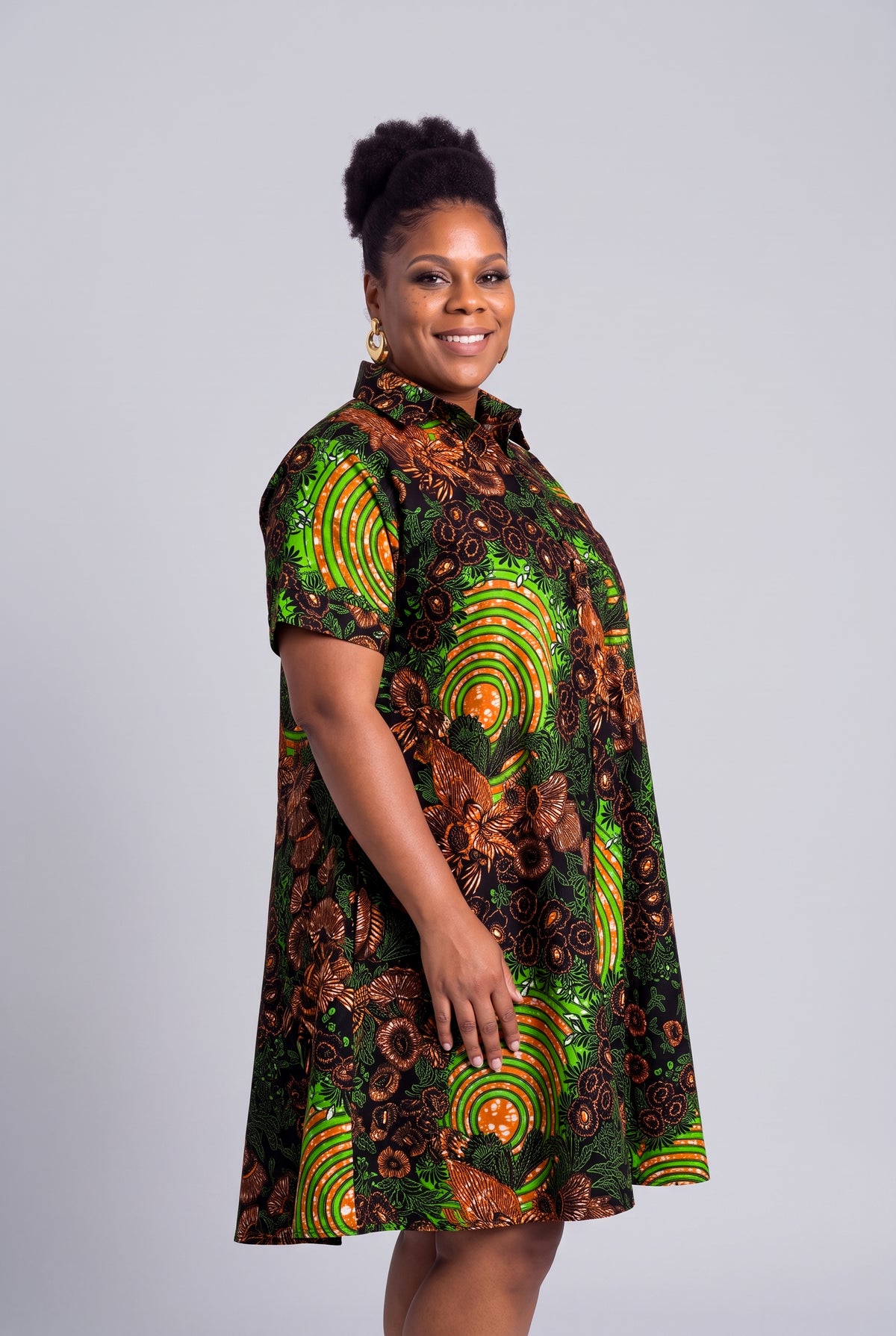 Side view profile of a curvy model wearing the green geometric Ankara shirt dress 