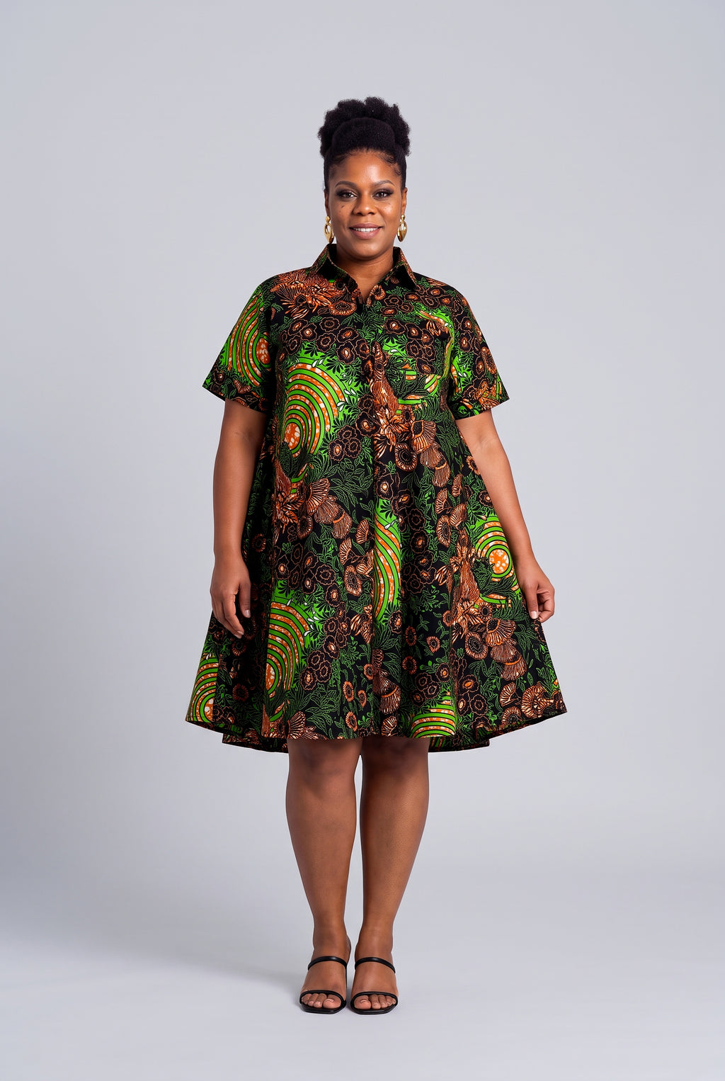 Model wearing Verdant Ripple green African print swing shirt dress with short sleeves and a relaxed flare