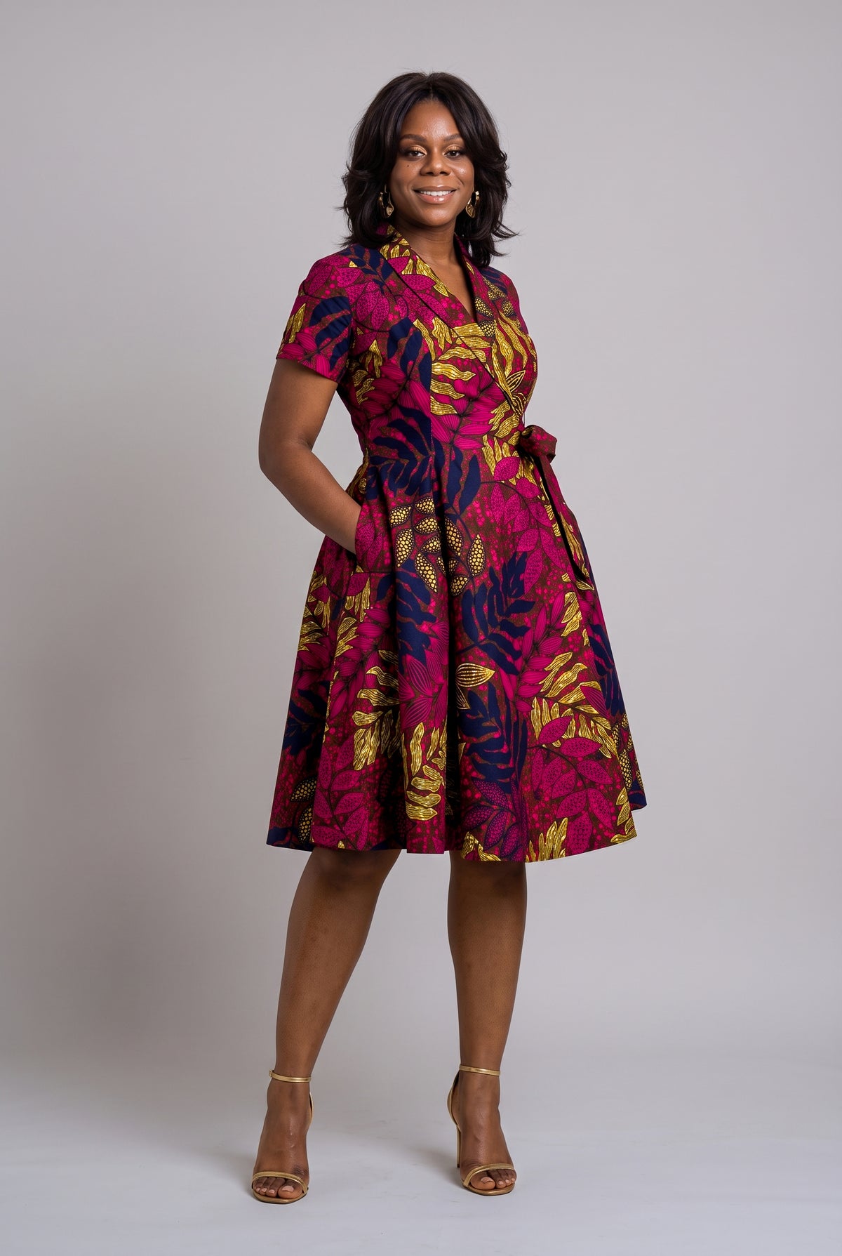 Front view of Pink African wax print wrap dress with hand in pocket