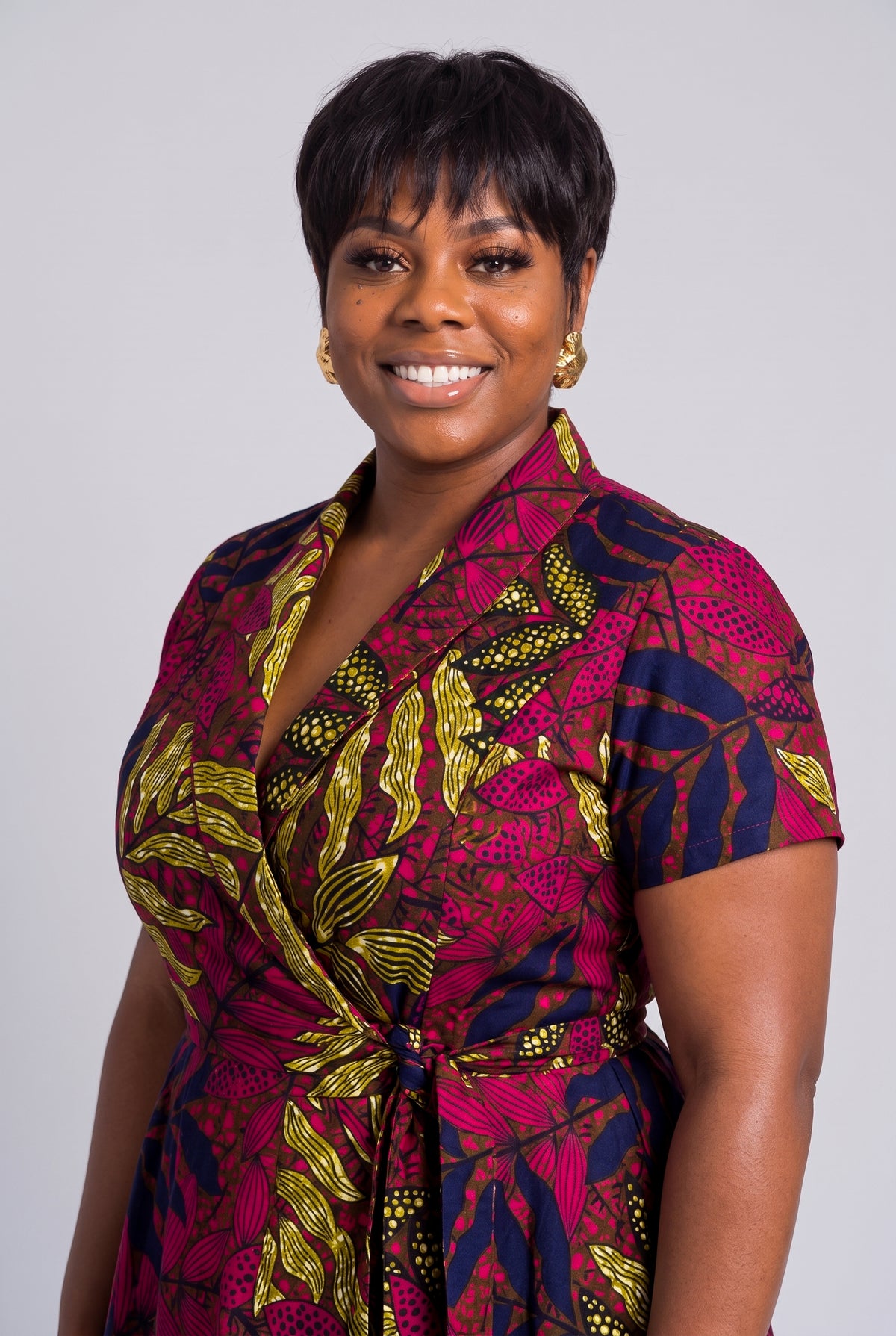 Three-quarter view of African print wrap dress in magenta and gold